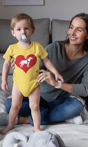 A baby in a yellow jumper with the I love guide dogs symbol