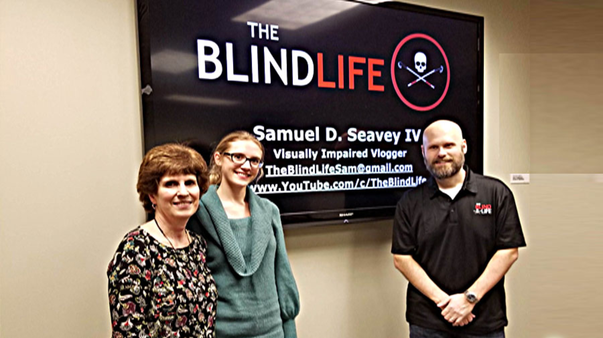 Sam Seavey in front of The Blind Life Poster  at a Speaking Engagement